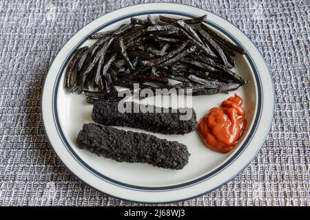 Une assiette de frites et de doigts de poisson très brûlés, noirs. Banque D'Images
