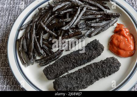 Une assiette de frites et de doigts de poisson très brûlés, noirs. Banque D'Images