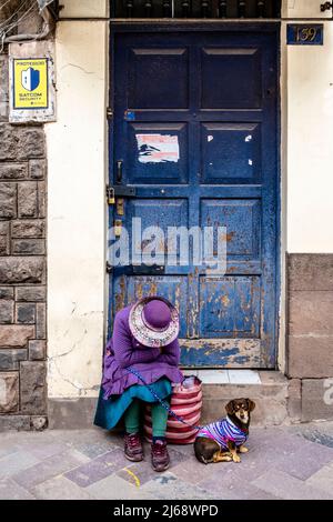 Une femme endormie dans Une porte avec son chien d'animal de compagnie, Cusco, province de Cusco, Pérou. Banque D'Images