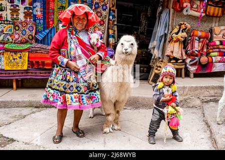 Une femme en costume traditionnel pose avec son PET Alpaca dans la ville de Pisac, la Vallée Sacrée, province de Calca, Pérou. Banque D'Images