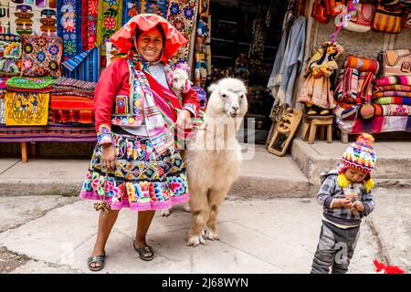 Une femme en costume traditionnel pose avec son PET Alpaca dans la ville de Pisac, la Vallée Sacrée, province de Calca, Pérou. Banque D'Images