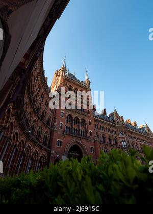 Hôtel Renaissance de St Pancras. Vue en angle bas avec un ciel bleu. Plantes vertes au premier plan de l'ancien bâtiment historique. Banque D'Images