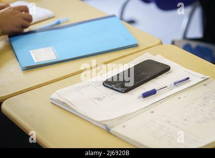 Mayence, Allemagne. 29th avril 2022. 29 avril 2022, Rhénanie-Palatinat, Mayence: Un téléphone portable se trouve sur la table d'un étudiant qui a fui l'Ukraine pendant les cours d'allemand au Gymnasium am Kurfürstendamm Schloss. Les étudiants ukrainiens sont autorisés au faire afin de rester en contact avec leurs parents à la maison. Plus de 5400 enfants et jeunes d'Ukraine sont actuellement inscrits dans des écoles de Rhénanie-Palatinat. En outre, selon le Ministère de l'éducation, 70 enseignants de nationalité ukrainienne et 51 autres enseignants de soutien linguistique ont été embauchés depuis la mi-février. Banque D'Images