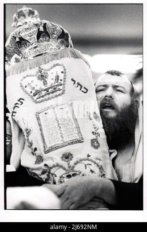 Aux services du matin de Sukkos, un homme qui dirige les services récite les prières tout en tenant un défilement de la Torah juste avant qu'il soit retourné à la Sainte Arche à la synagogue principale de Lubavitch en 1983 Banque D'Images