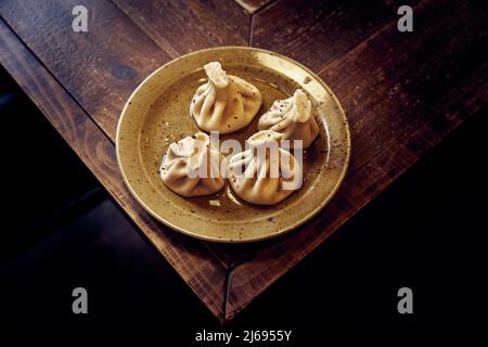 Cuisine géorgienne. Appétissant khinkali de viande d'agneau dans une assiette en céramique sur une table en bois Banque D'Images