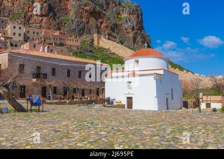 Monemvasia, Grèce - 31 mars 2019: Panorama de rue avec maisons anciennes et église Panagia Chrysafitissa dans la ville ancienne, Péloponnèse Banque D'Images