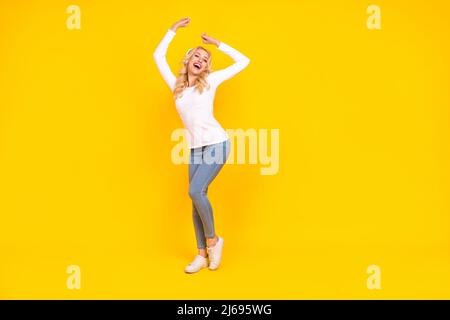 Photo de corps complet de hooray millénaire blonde femme danse vêtements chemise jeans chaussures isolées sur fond jaune Banque D'Images