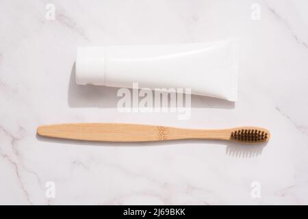 Brosse à dents en bambou et tube en bois avec dentifrice minéral biologique sur fond de table en marbre blanc. Tube en plastique blanc avec dentifrice. Produ. Bain éco Banque D'Images