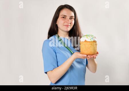 Le médecin tient un gâteau de Pâques et sourit, un endroit pour le texte. Pâques médicales Banque D'Images