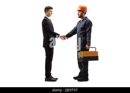 Prise de vue sur toute la longueur d'un travailleur en uniforme avec une boîte à outils qui se secoue les mains avec un jeune homme isolé sur fond blanc Banque D'Images