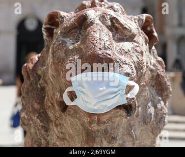 Venise, VE, Italie - 13 juillet 2020 : détail de la statue du lion en marbre avec masque chirurgical pendant le verrouillage italien Banque D'Images