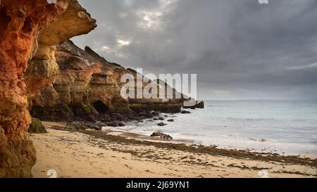 Hautes falaises surplombant la plage et la mer par une journée nuageux, paysage océanique de Pintadinho, Algarve, Portugal, Europe Banque D'Images