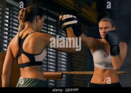 Jeune femme forte ayant un entraînement de boxe avec son entraîneur sur carré anneau de tir horizontal Banque D'Images