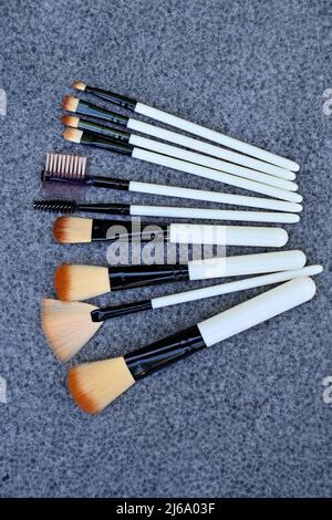 gros plan sur le faisceau blanc brun kit de maquillage brossez sur fond gris brun non focus. Banque D'Images