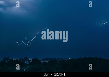 La foudre dans le ciel au-dessus de la ville. Des clignotements lumineux la nuit sombre. Les orages et les décharges d'électricité dans l'atmosphère. Paysage urbain nocturne. Banque D'Images