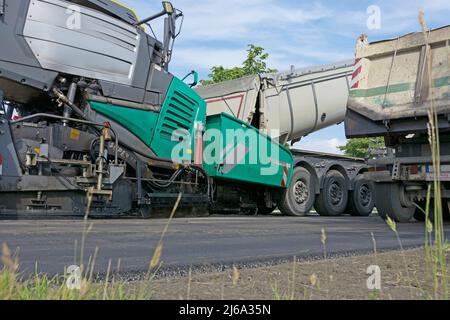 le finisseur routier moderne s'accumule dans l'asphalte et est chargé par camion Banque D'Images