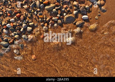 Directement au-dessus de Flatlay de vagues douces Lapping Sand et Pebble Beach avec l'eau claire et fraîche immaculée Banque D'Images