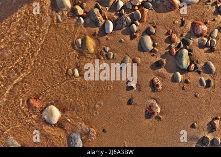 Directement au-dessus de Flatlay de vagues douces Lapping Sand et Pebble Beach avec l'eau claire et fraîche immaculée Banque D'Images