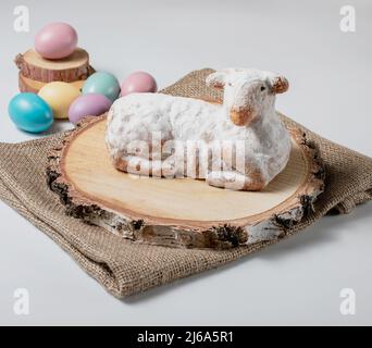 Gâteau traditionnel d'agneau doux de pâques avec sucre en poudre, œufs, bois et sac sur fond blanc, photo de stock Banque D'Images