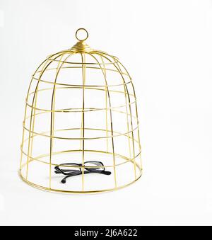 Grande cage à oiseaux dorée et verres noirs sur fond blanc, concept, photo de stock Banque D'Images