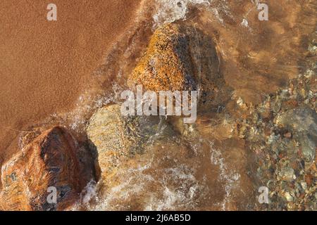 Directement au-dessus de la photo de petites vagues qui se roulent dans la plage parsemée de rochers et de Boulders colorés Banque D'Images