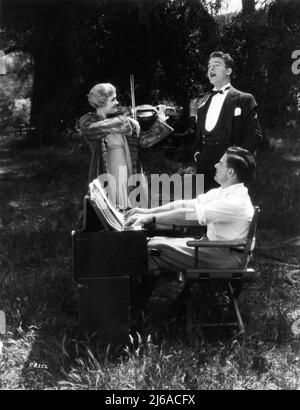 LAURA LA PLANTE NEIL HAMILTON et le réalisateur WILLIAM WYLER sur le lieu de tournage Candid faire de la musique d'ambiance pendant une pause dans le tournage du PIÈGE DE L'AMOUR 1929 réalisateur / producteur WILLIAM WYLER sorti comme Silent film et comme Silent Movie avec des séquences de conversation Universal Pictures Banque D'Images