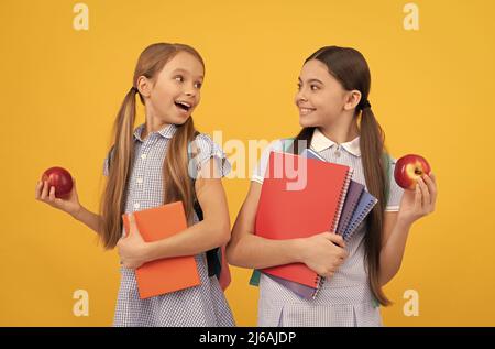 Refaites le bon début de l'école. Les enfants heureux tiennent des livres et des pommes. Une alimentation saine. Nutrition scolaire Banque D'Images