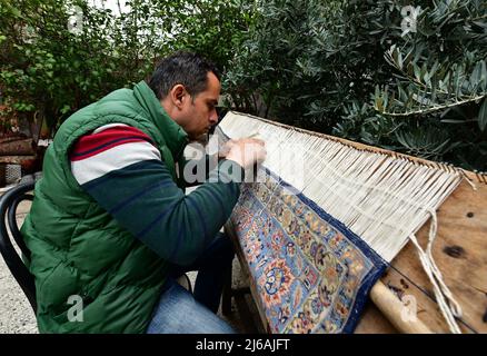 (220429) -- ALEP (SYRIE), 29 avril 2022 (Xinhua) -- Omar Rawas, un tisserand de tapis, répare un tapis dans son atelier d'Alep (Syrie), le 8 mars 2022. Avant l’éruption de la guerre en Syrie en 2011, la réparation des tapis était principalement destinée à réparer les tapis artisanaux anciens et coûteux, considérés comme du patrimoine et des trésors en raison de leur valeur. Cependant, la situation a changé maintenant que les gens ne peuvent guère se permettre de nouveaux tapis coûteux dans un contexte de crise économique résultant des longues années de guerre et des sanctions économiques sévères imposées par les États-Unis à la Syrie. (Photo par Ammar Safarj Banque D'Images