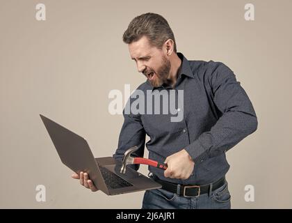 Colère incontrôlée.Un homme fou a frappé un ordinateur portable avec un marteau.Vous vous sentez frustré et fou Banque D'Images