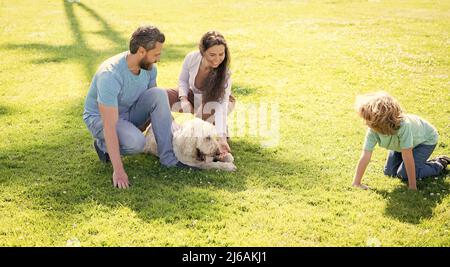 bonne famille de maman père et fils enfant jouant avec chien d'animal de compagnie dans l'herbe verte du parc d'été, amoureux de chien Banque D'Images