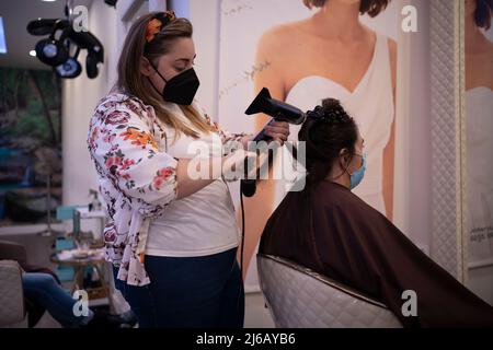 Coiffeur coiffeur coiffant les cheveux du client avec un peigne et un sèche-cheveux Banque D'Images