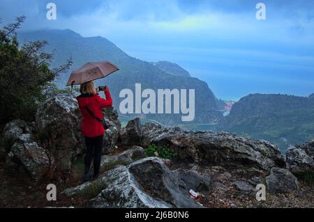 Vue arrière de la femme avec un parapluie debout sur le sommet de la colline par temps pluvieux Banque D'Images