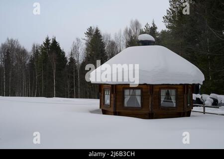 Rovaniemi, Finlande - 18th mars 2022 : cabine en bois dans une forêt de sapins enneigés en Finlande. Banque D'Images