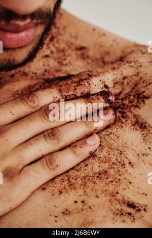 Gros plan d'un jeune homme appliquant un gommage sur son corps et faisant un massage Banque D'Images