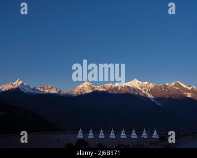 pagodes blanches du temple feilai avec la montagne de neige de meili au lever du soleil en arrière-plan dans la province chinoise du yunnan Banque D'Images