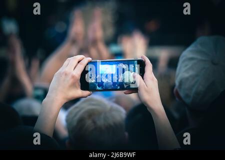 Les jeunes prennent des photos ou des vidéos d'un concert sur leur smartphone. Banque D'Images