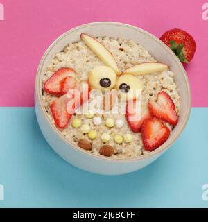 Petit déjeuner à base de flocons d'avoine créatif pour les enfants sur fond coloré. Idée de petit déjeuner sain. Déjeuner ludique. Banque D'Images