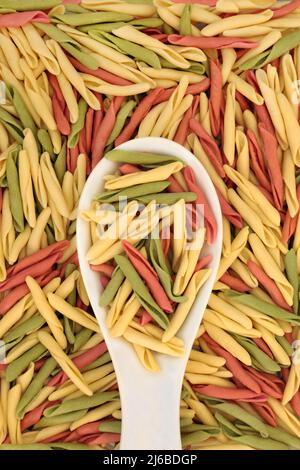 Fusilli pulgiesi tricolor pâtes alimentaires santé dans une cuillère en porcelaine et formant un fond abstrait. Spécialité cuisine italienne saine. Banque D'Images