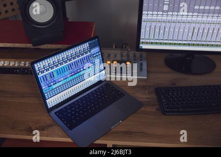 Vue de dessus de l'ordinateur portable allumé et de l'écran du moniteur sur une table dans la salle d'ingénieur du son d'un studio de radiodiffusion et d'enregistrement Banque D'Images