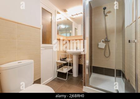 Salle de bains avec lavabo en porcelaine blanche sur pied assorti, miroirs sans cadre et cabine de douche avec porte en verre Banque D'Images