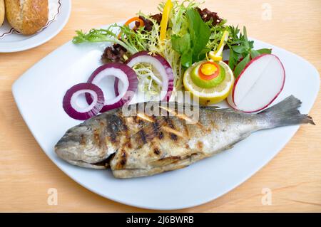 dorado au poisson cuit au four. Poisson grillé et salades, poisson cipura cupra, dans une assiette à dîner blanche Banque D'Images