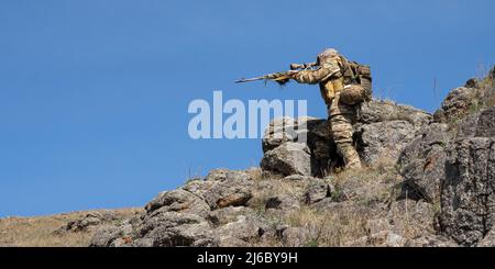 Embuscade dans les montagnes - sniper professionnel des forces spéciales visant l'ennemi dans les montagnes. Concept d'opérations militaires modernes et d'un spécial Banque D'Images