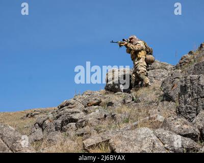 Sniper professionnel des forces spéciales visant l'ennemi dans les montagnes. Embuscade dans les montagnes. Le concept des opérations militaires modernes et une spécification Banque D'Images