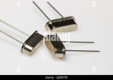 Résonateur en cristal dans un corps métallique sur fond blanc. Composants électroniques. Banque D'Images