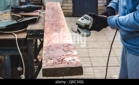 un homme meule une planche. Élimination de l'ancienne peinture des panneaux. Travail de menuiserie. Concentration sélective Banque D'Images