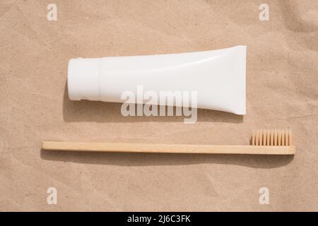 Brosse à dents en bambou et tube en bois avec dentifrice minéral biologique sur fond de papier kraft. Tube en plastique blanc avec dentifrice. Produits de bain écologiques, Mo Banque D'Images