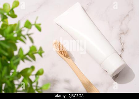 Brosse à dents en bambou et tube en bois avec dentifrice minéral biologique sur fond de table en marbre blanc. Tube en plastique blanc avec dentifrice. Produ. Bain éco Banque D'Images