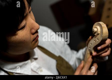 Jeune femme chinoise de violon travaillant avec la gouge pour faire un nouveau violon dans son atelier Banque D'Images