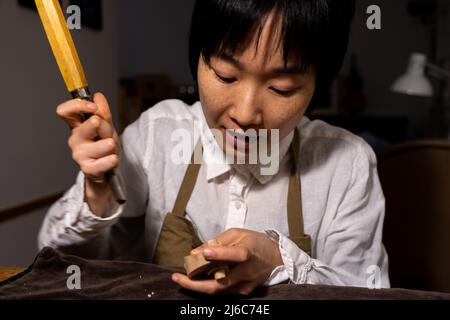 Jeune femme chinoise de violon travaillant avec la gouge pour faire un nouveau violon dans son atelier Banque D'Images