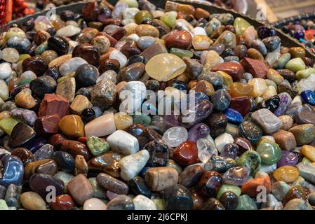 Galets colorés, rochers mouillés sur la plage de la rivière. Différentes pierres de galet nature lisse (vert, orange, gris, rouge) comme le motif abstrait de roche naturelle te Banque D'Images